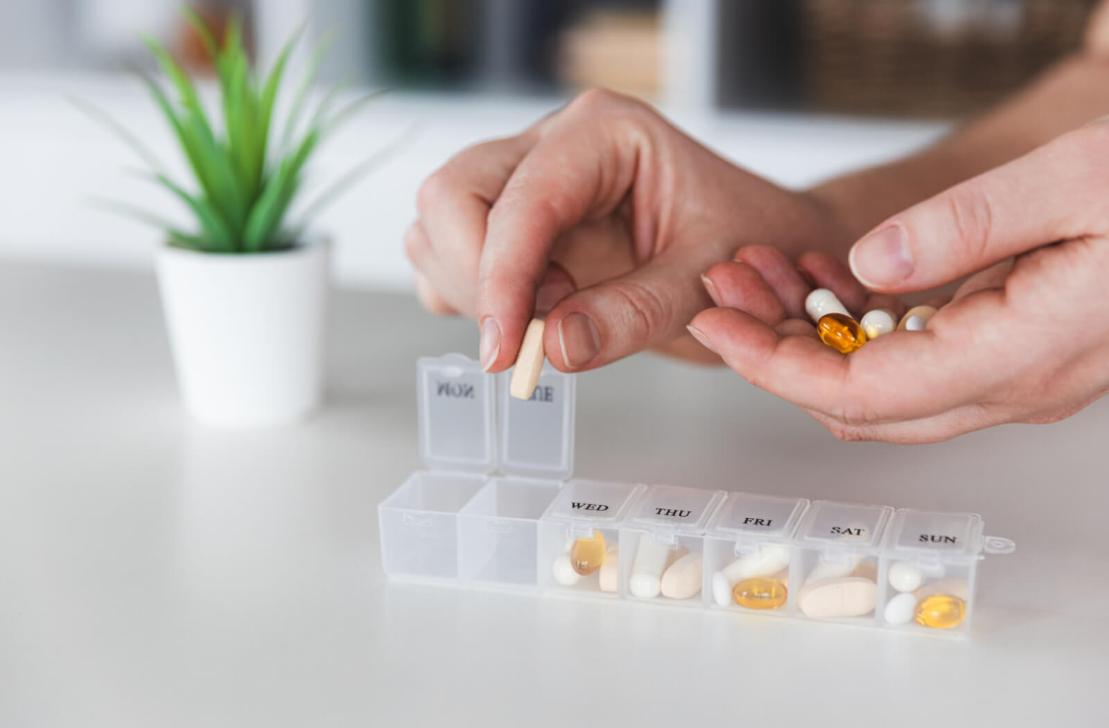 A personal care professional replenishes medications and supplements in a medication dispenser.